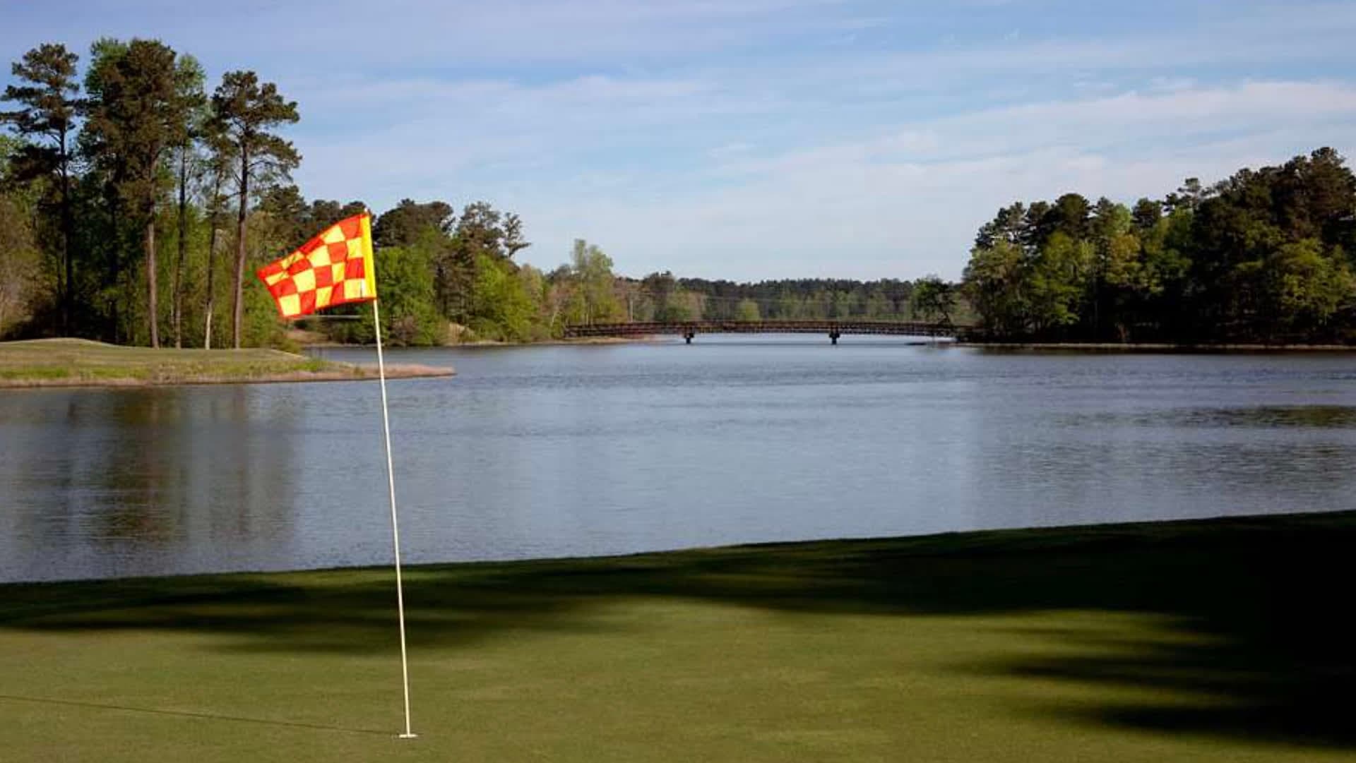 A green at Grand National on the Robert Trent Jones Trail, the iconic checkered pin flag against the water
